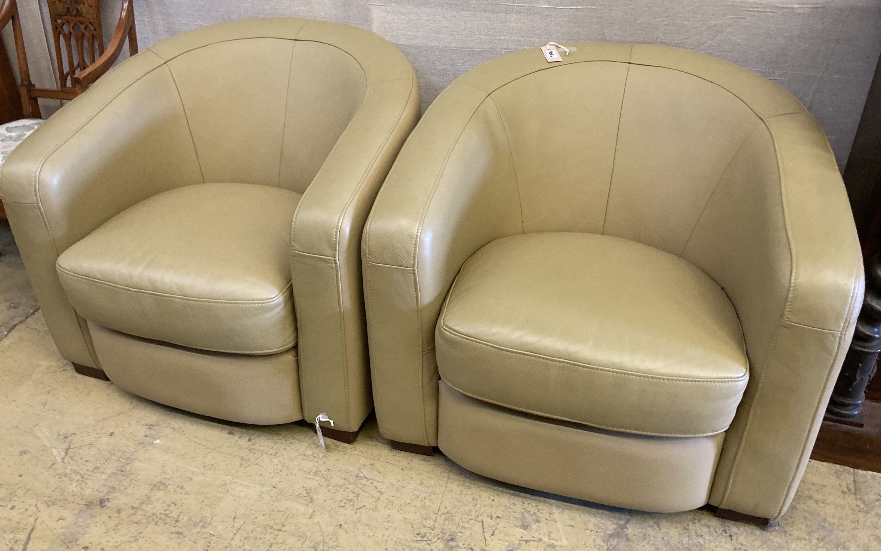 A pair of tub chairs upholstered in cream leather, width 86cm, depth 75cm, height 74cm